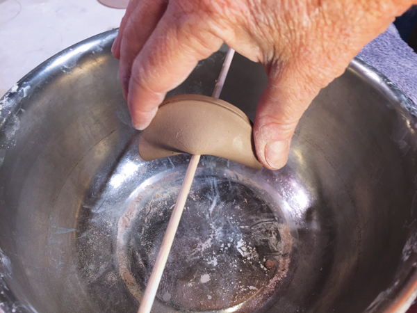 3 Gently push the center of the folded side over a thin wooden skewer, curving the ends in.