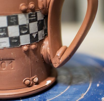 3 Attach struts to the mug, attach the handle to the struts, and add a coil to the joint.