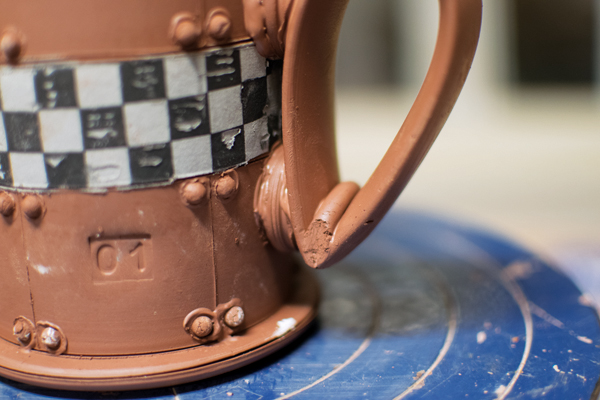 12 Attach struts to the mug, attach the handle to the struts, and add a coil to the joint.