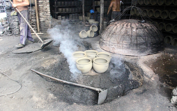 2 The still smoldering reduction pit with surrounding moat prepared to hold water. Several pots are warmed up on top of the pit lid.