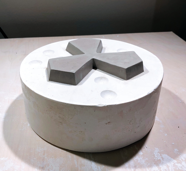 4 Fill in the negative space in the first mold part with clay. Place the back of the prototype onto the first mold part. Add or remove clay to create a seamless connection with the front of the prototype in the first mold part.