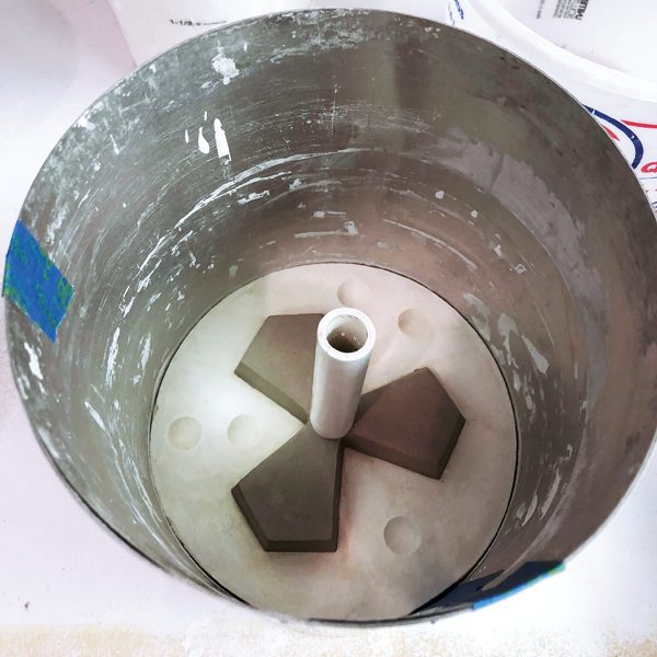 5 Place a PVC pipe in the back of the tile form to create a pour hole. Use aluminum flashing to contain the plaster when pouring it onto the first mold part. 