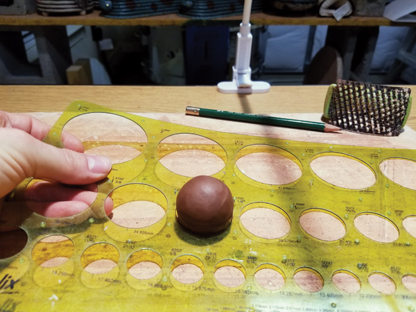 1 Measure out enough clay to make a 1 1/4-inch ball. Tap against the work surface, rotating frequently until 6 flat sides are established.
