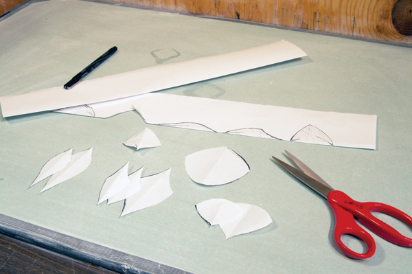 2 Draw half of each shape onto the edge of a folded piece of paper. Cut along the line, but not the fold, to create symmetrical shapes.
