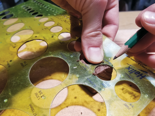 4 Use a template and a pencil to mark circle shapes onto the cube, thinking ahead while placing them to consider application of color.