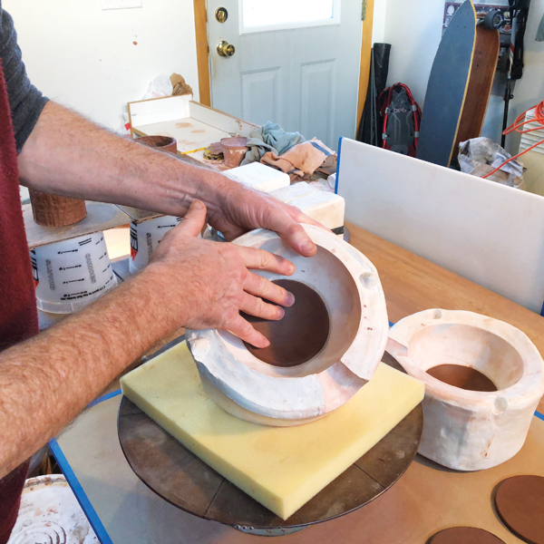 6 Cut a disk of clay from a slab and press it into a plaster mold to form a base.