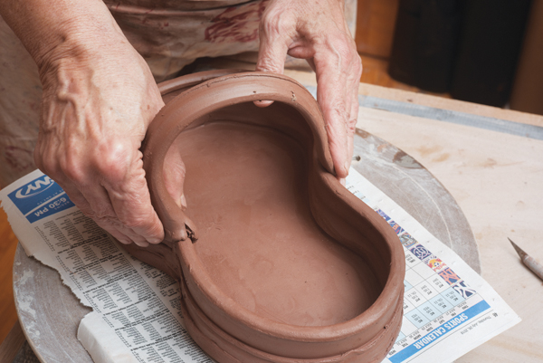 6 Pull a thick strap handle. Once it can hold its shape, attach it to the tray walls where they cinch in the middle.