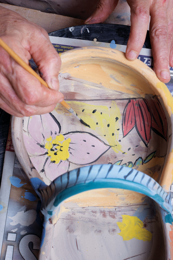 17 After the layers of colored slip are added, paint linear black elements and other details using a smaller brush.