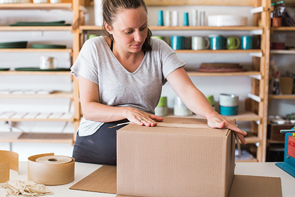 1 Secure the bottom flaps of a cardboard box by pressing a piece of dampened paper tape along the seam.