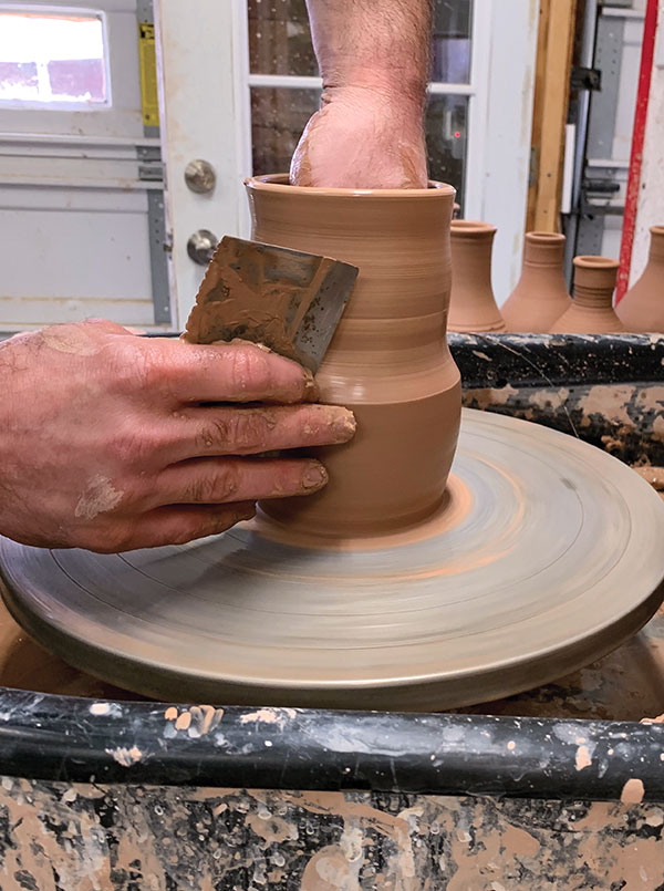 1 Use a metal rib to remove excess clay at the foot and create a belly at the bottom.