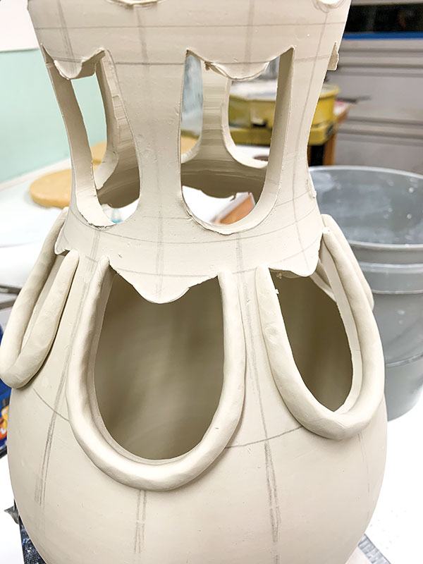 7 Roll tapered coils and attach them to the exterior wall of the vase around the cutouts to reinforce each opening.