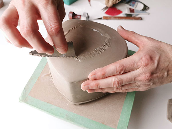 9 Score a ring the size of the lid assembly onto the teapot top, then add slip to prepare for attaching the lid assembly. 