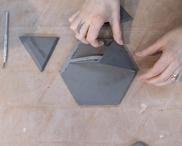 6 Next, score, slip, and attach the triangular slab walls to the trapezoidal shelf and the hexagonal base. 