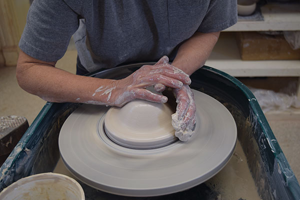 1 Center 3 pounds of clay and use the edge of your hand to push down the outer edge of the cone of clay.