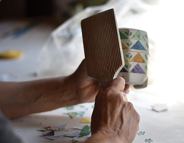 14 Once the pattern is complete, use a wooden paddle to press the paper into the clay. 