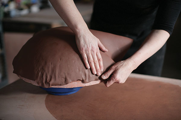 3 Use the palm of your hand to gently press the slab against the bisque form. 