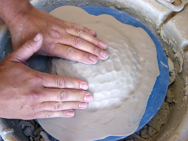 8 Compress the slab into the detail of the bisque mold with your fingertips.