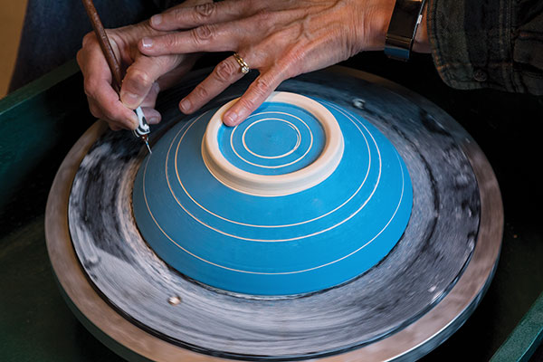 2 Carve horizontal concentric rings with a compass or center the pot on the wheel and carve lines as the wheel spins.