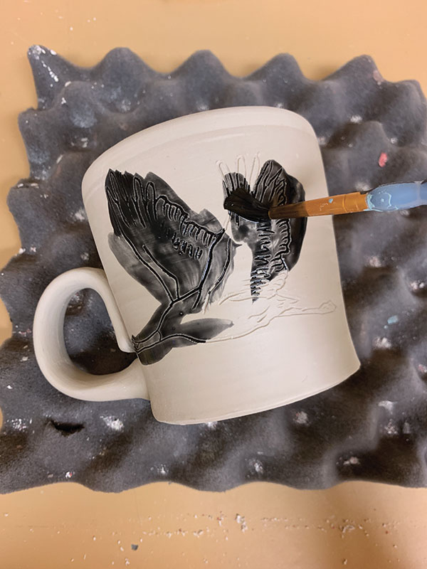 3 Use a paint brush to apply watered-down underglaze onto the drawing. Let the underglaze dry completely.