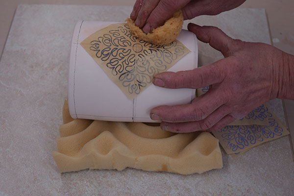 8 Draw a grid on the pot, place the decal, and dab it with a damp sponge to wet.