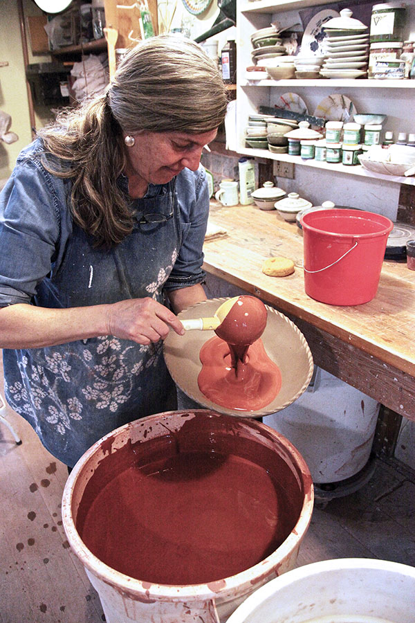 3 Ladle slip into the dish, then move it around the edge and pour it out. Use a squeezed-out sponge to clean any excess slip off of the exterior.
