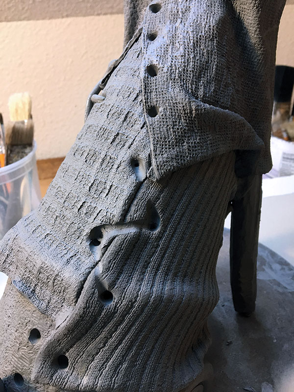 6 Attach textured slabs to the clay armature and add holes for extruded clay stitching.