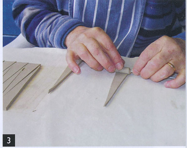 3 Brush each triangle with water, then roll it around a wooden dowel.