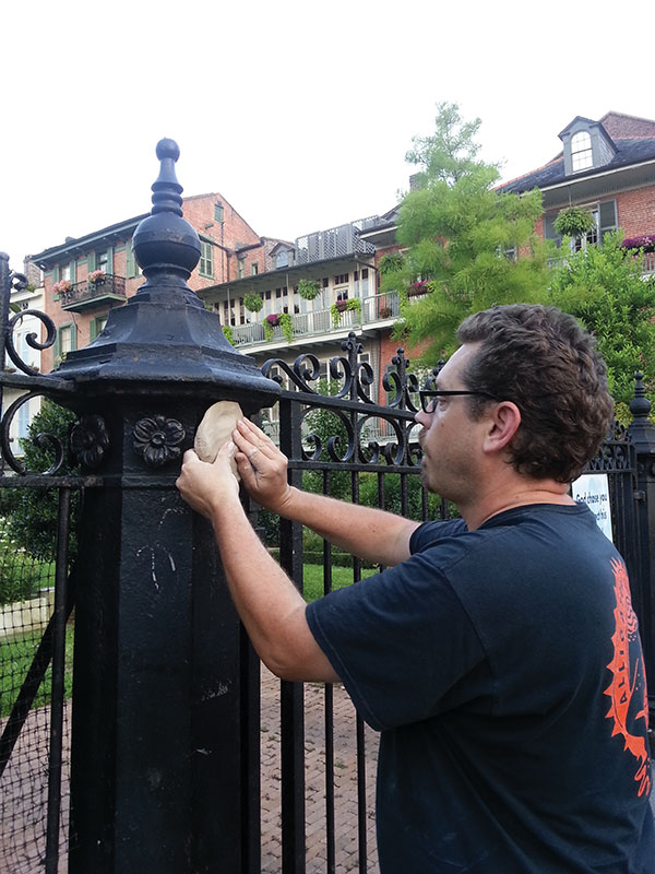 4 Pressing a wet slab onto an old iron fence. Work the clay into the surface by pressing every inch with your fingertips. 