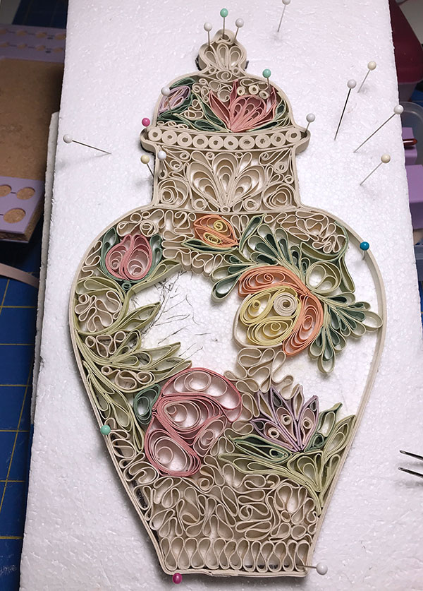 F The strips are assembled on pieces of foam and held in place with pins using traditional paper-quilling techniques and tools. The quilled components are attached together using slip. After they dry Jakielski removes the pins and carefully slides the piece from the foam onto a kiln shelf.