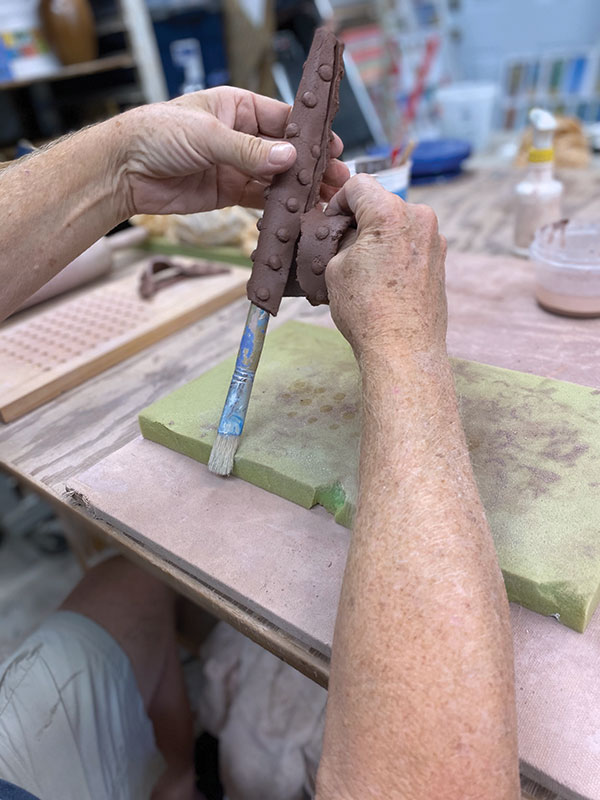 11 Use a paintbrush handle to form a long cone by wrapping the slab around it. Overlap and blend the edges together.