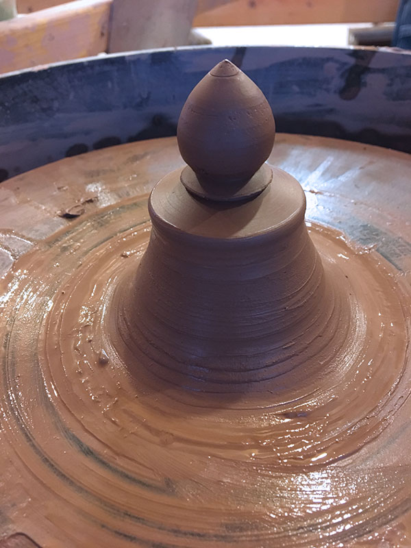 9 Throw a knob for the lid of the butter dish on the wheel by throwing off the hump.