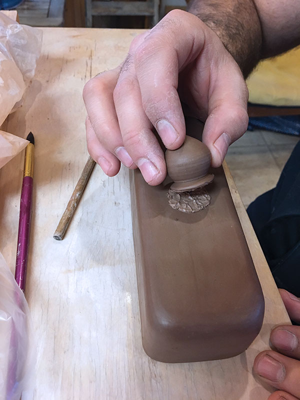 10 Score and slip the area where the knob will be attached to the lid, then join the two pieces together.
