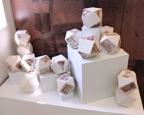 5 Postmarked (installation view at the Gardiner Museum, Toronto), 6 in. (15 cm) in height each, 21 slip-cast porcelain tetrahedrons, iron-oxide ceramic decals, 2017. Photo: Josie Slaughter.