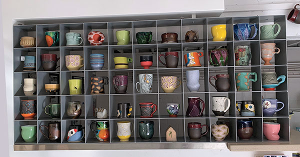 Cup-grid display at Plinth Gallery in Denver, Colorado, showcasing cups, mugs, and sculpture by more than 25 artists, available for purchase. 
