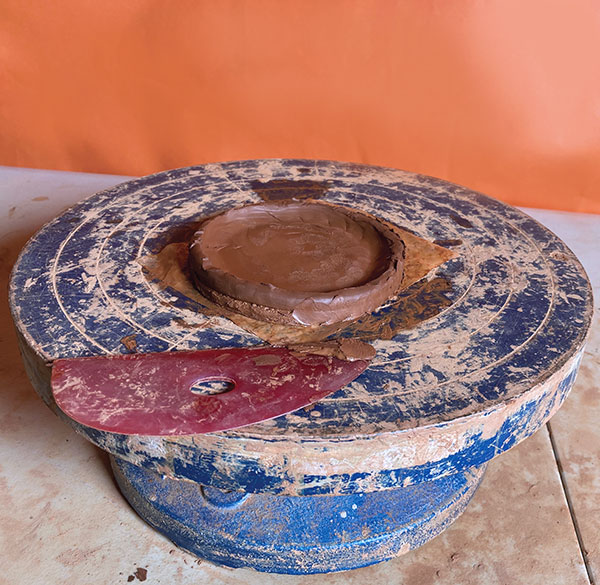 1 Score and slip one coil of clay onto a small round slab on a banding wheel.
