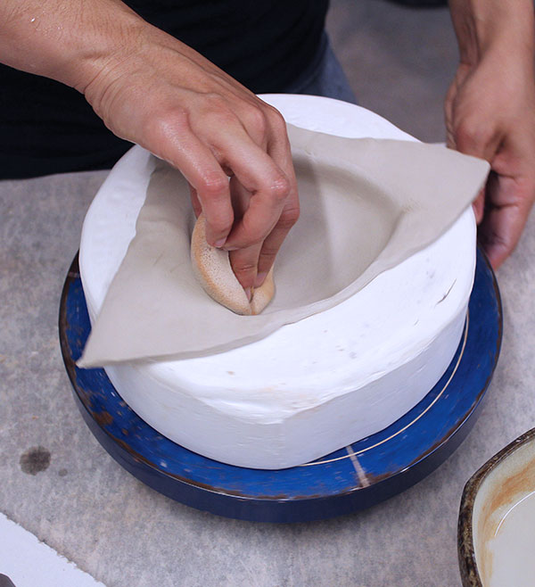 2 Roll out and rib a ½–¾ inch-thick slab. Gently press it into the mold. Use a damp sponge to press into the corners of the mold.