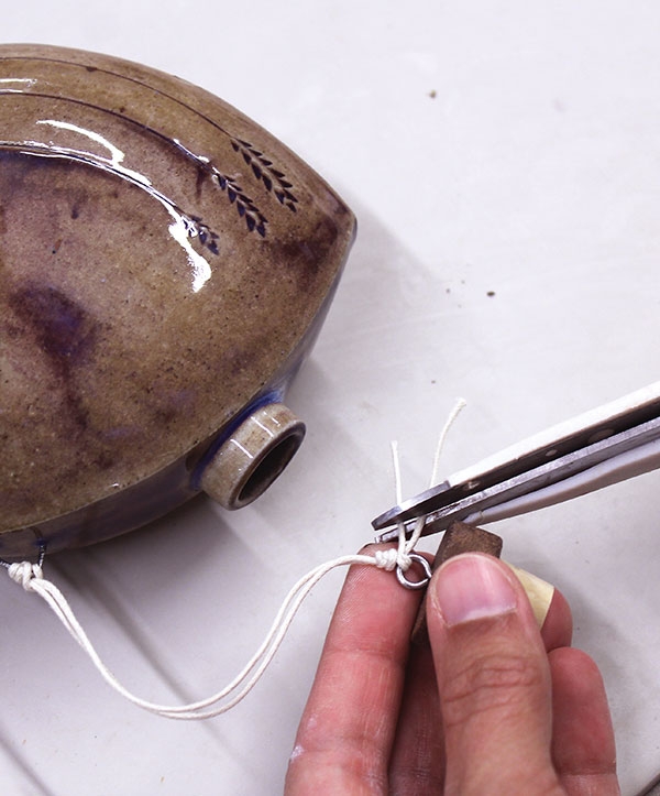 10 Insert a small eye screw into a wooden capped cork. Tether the screw to the body of the flask with a cotton cord.