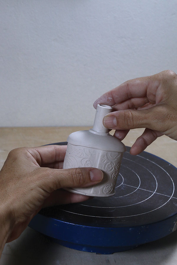 13 Mark the outline of the neck on the top of the bottle, cut a round hole on the top, then score, slip, and attach the neck.