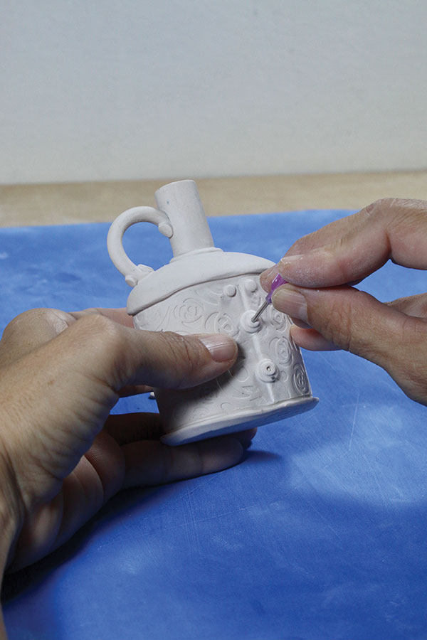 17 Using decorating piping tips, cut small discs and place them onto the body. Use a slip-trailing tip to add the details.