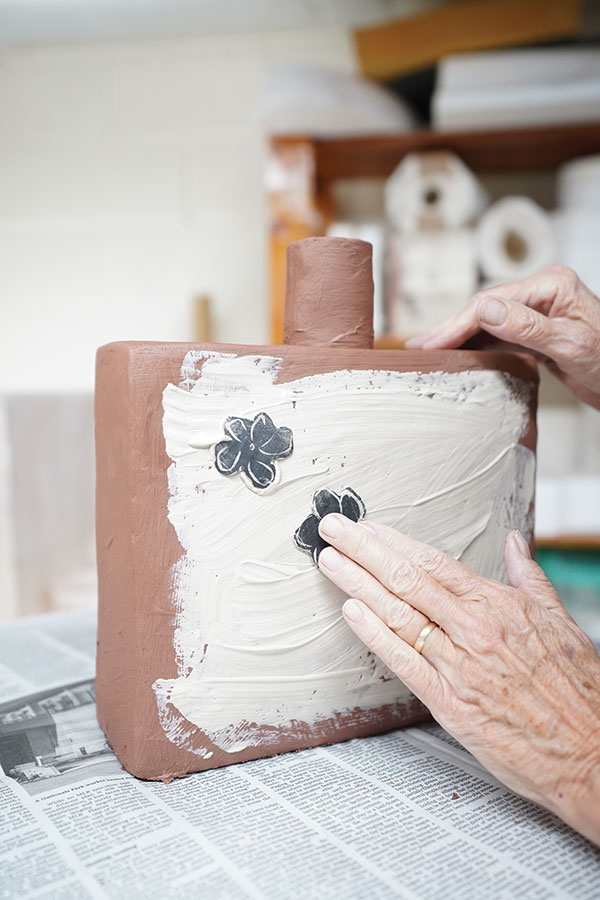 14 Immediately begin pressing on the cut-out clay flowers while the white slip is damp.