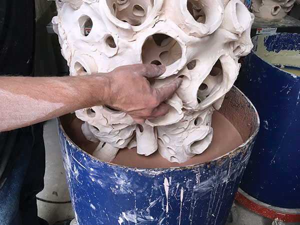 9 Miles slowly lowering the sculpture into the glaze.