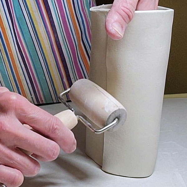 5 Score, overlap, and compress the edges of a cylinder together to form the pitcher.