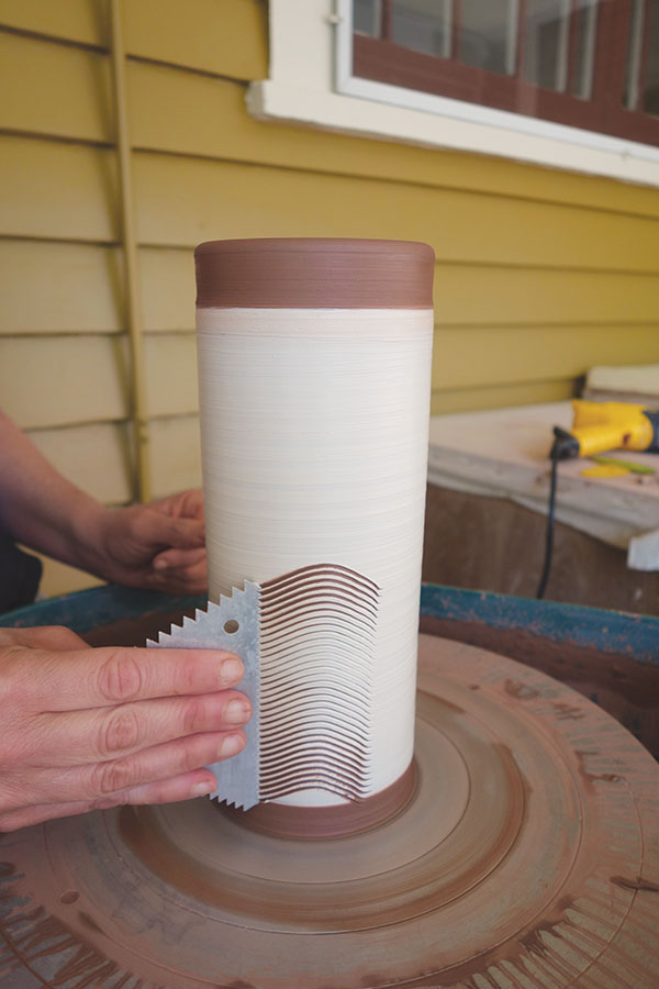 6 With the wheel spinning slowly, hold the cake-decorating comb vertically against the cylinder and swipe it through the slip.