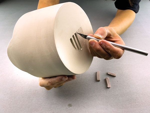 7 Sketch and cut out the planter's drainage holes on the bottom of the larger cylinder.