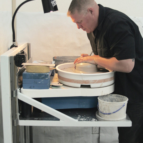 1 Center a 5-pound ball of clay. Rather than bracing your forearms on your legs, brace them on the edge of splash pan.