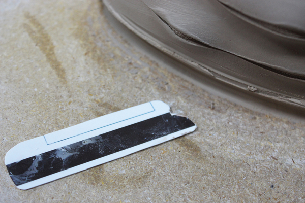 7 Compress the excess clay from the slab into the wall of the form. Cut a profile for the base into an old credit card.