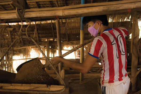 3 A workshop employee shovels Myanmar mountain clay into a large sifter.