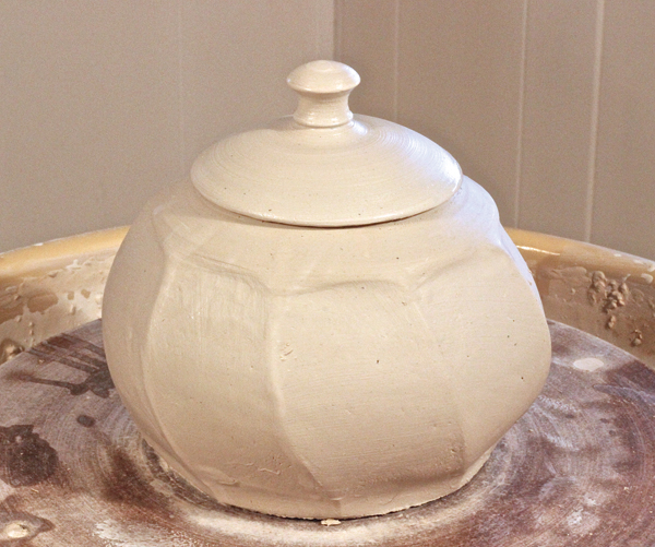 E Add a small piece of clay to the top and throw it into a knob, then define the edge.