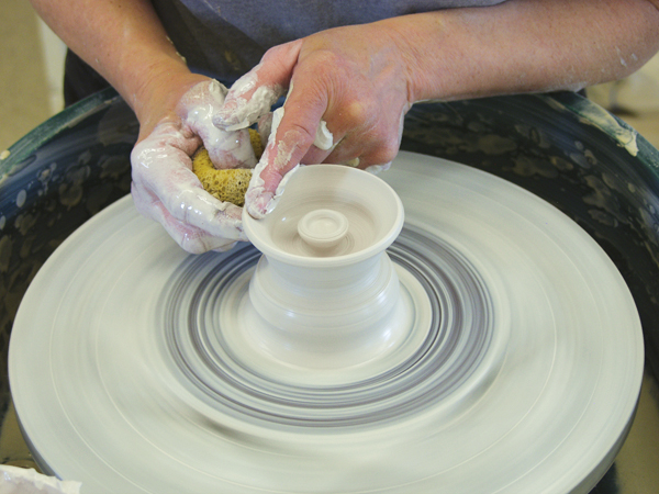 5 Shape the knob so it’s easy to grasp. Then, pull up the clay around it, flatten the rim, and measure it so it fits the cup.