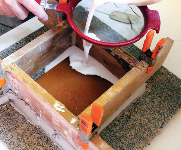 4 Pouring the plaster negative cavity from the master rubber positive that was created first.